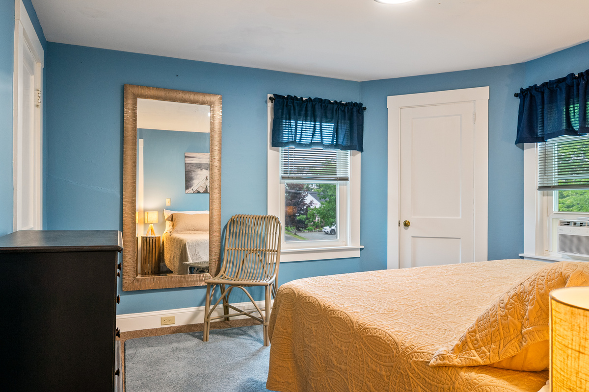 Step through the entrance from the landing and take in the relaxed, open feel of the primary suite. The expansive full-length mirror, classic wicker seating, and rich blue walls create an organized, inviting space to get ready for a day of exploring.