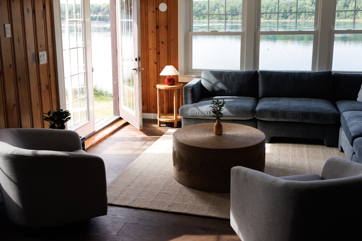  Settle into the living room from the far end and take in how much light pours through — windows on three sides, cove always in the frame.