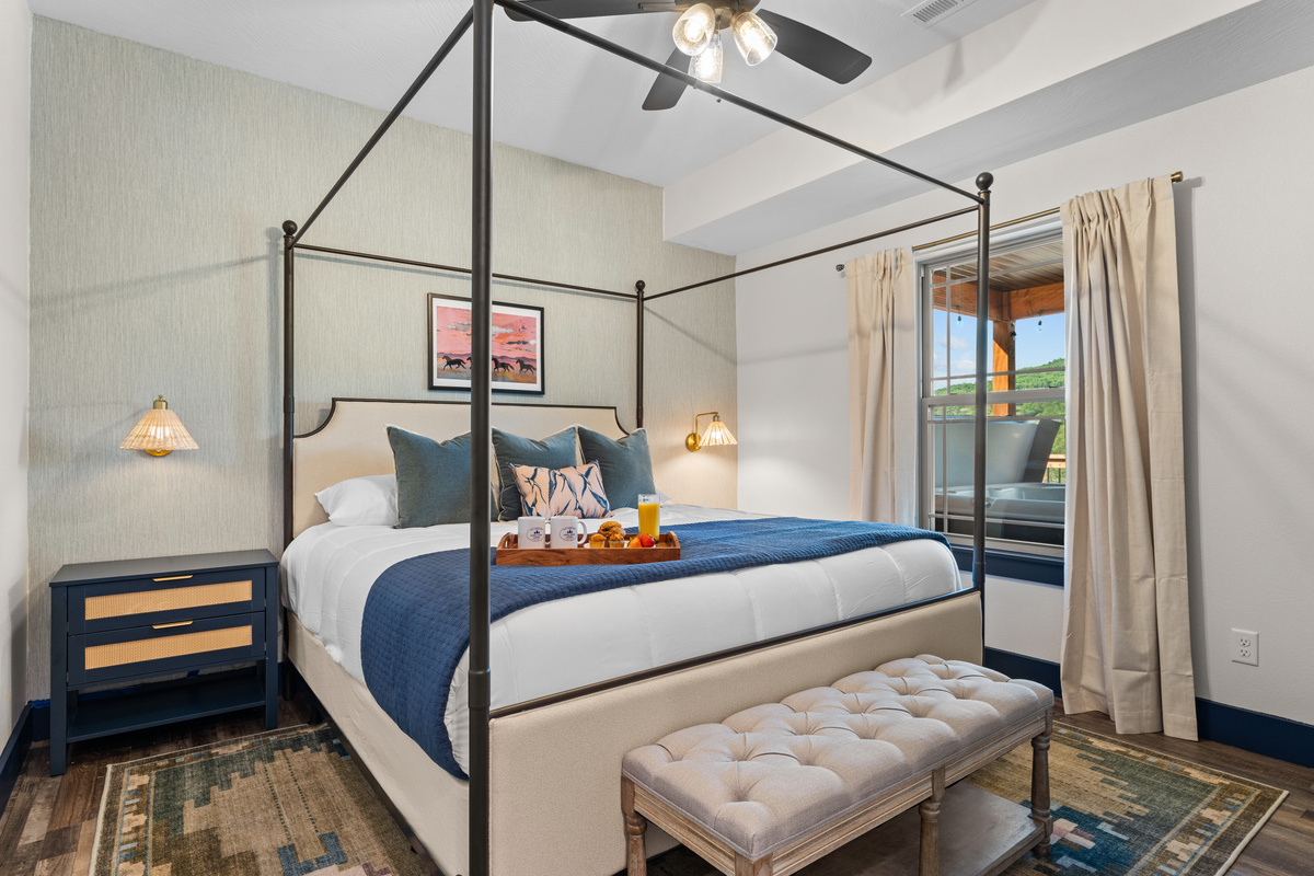 Unwind in the Fort Worth King room, a main level bedroom with a canopy king bed, Smart TV, and a view over the Ozark hills.