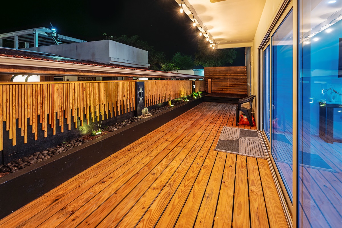 Wide night-time view of the wooden deck with string lights and planters