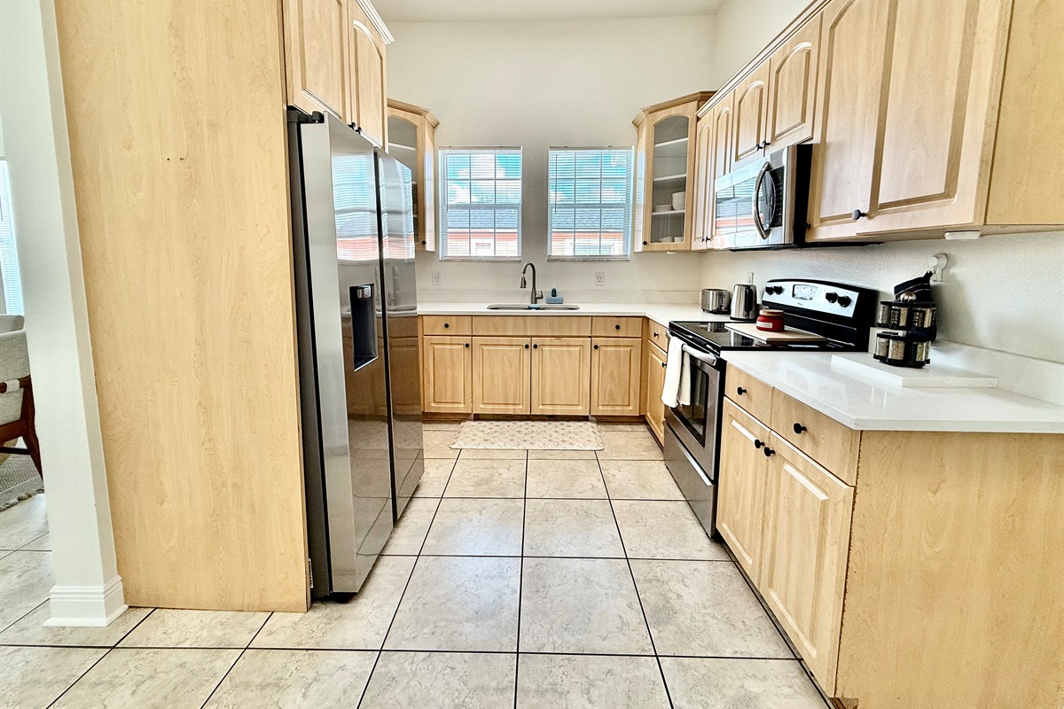 Bright and open kitchen featuring sleek appliances, ample counter space, and a warm, natural wood aesthetic.