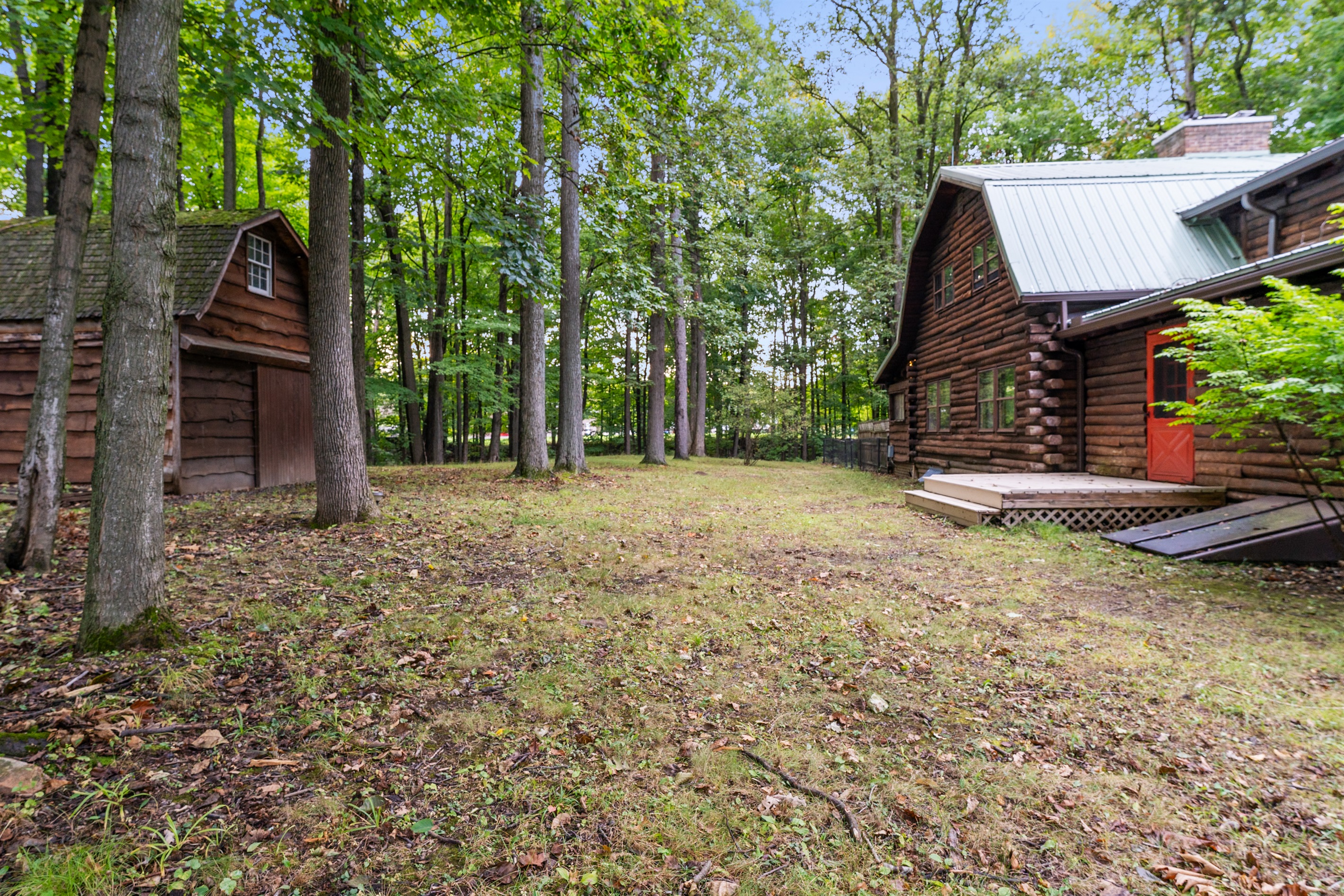 Explore the cabin’s expansive yard with rustic outbuildings, creating a true woodland retreat feel.