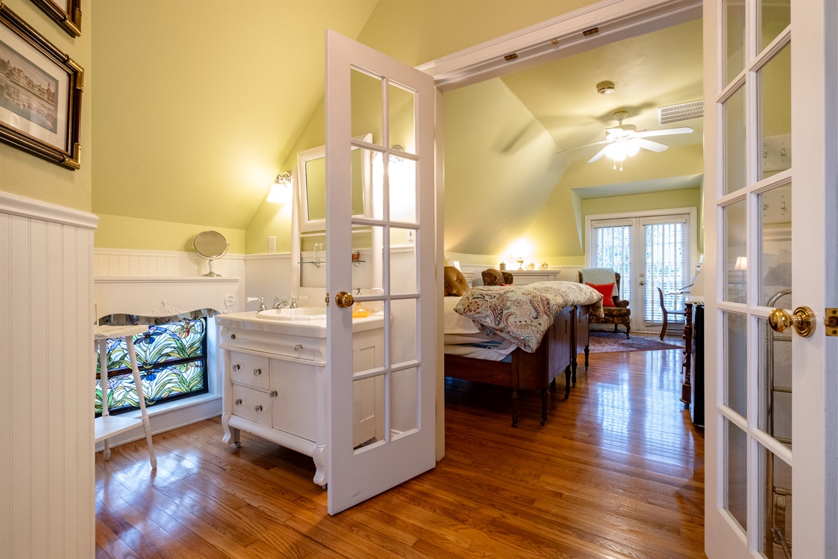 Bathroom-to-bedroom view highlighting the suite’s spacious layout and natural light flow.