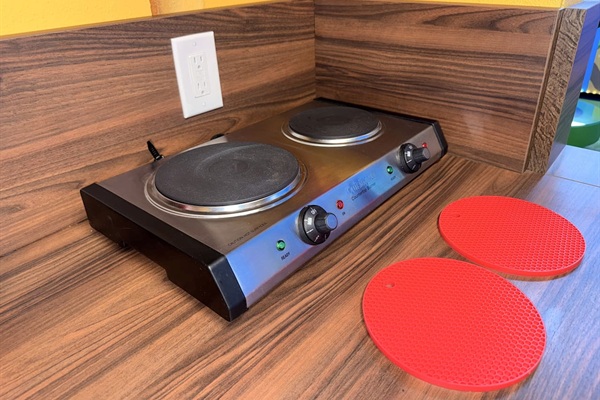 Ready-to-cook PORTABLE electric stovetop in the full compact kitchen at Mario's Mini Mansion, nearOrlando, FL! Smooth black cooktop, red silicone trivets, & wood counters provide everything you need for delicious family meals in this themed getaway.