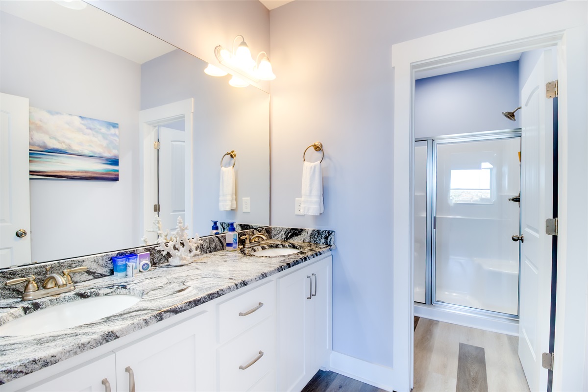 Bright Master bathroom's double vanity with granite counters, warm lighting, and plenty of space to get ready