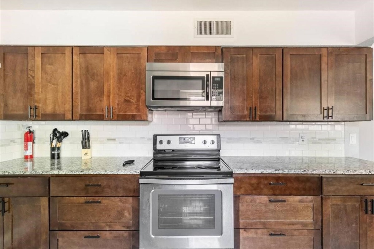 Kitchen with granite countertops and cooking tools and dinning ware.