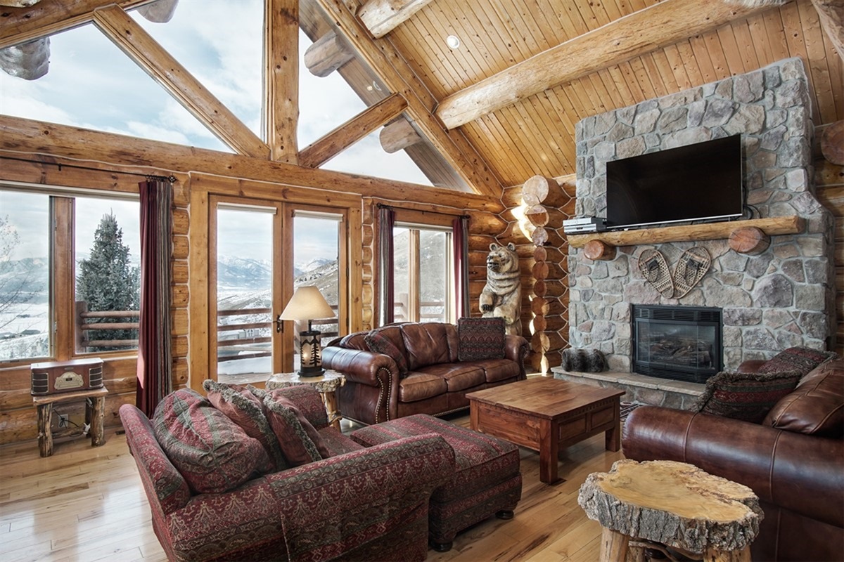 Warm and inviting living area with stone fireplace and panoramic windows