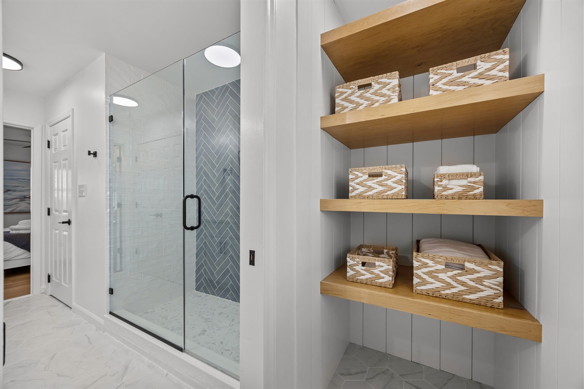 1st floor master bathroom storage shelves stocked with towels and essentials