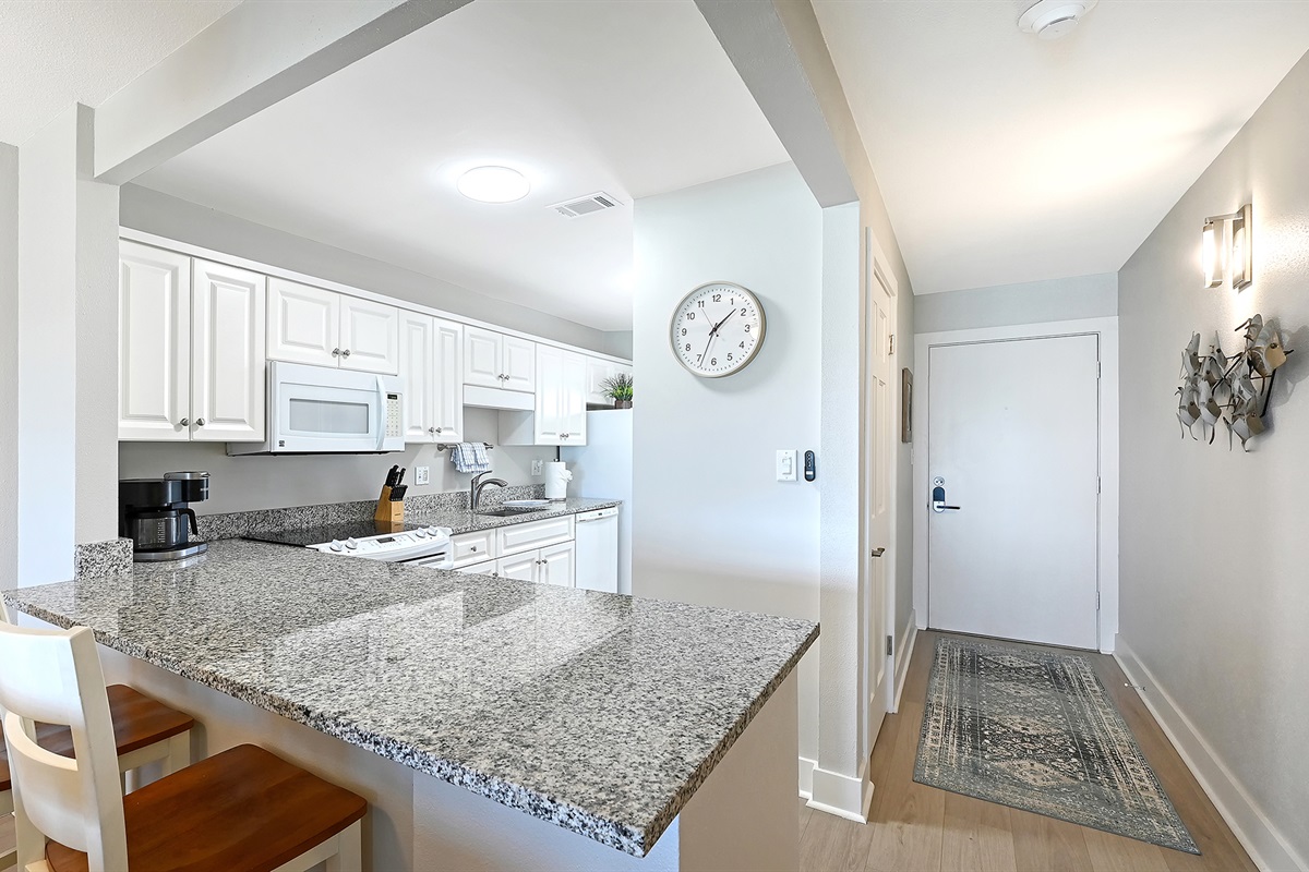 A serving counter with bar stools, to entrance door