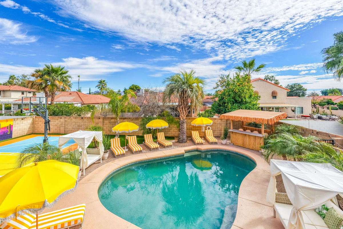 Resort-style pool area with loungers, yellow umbrellas, and desert views—a vacation oasis steps from the home.