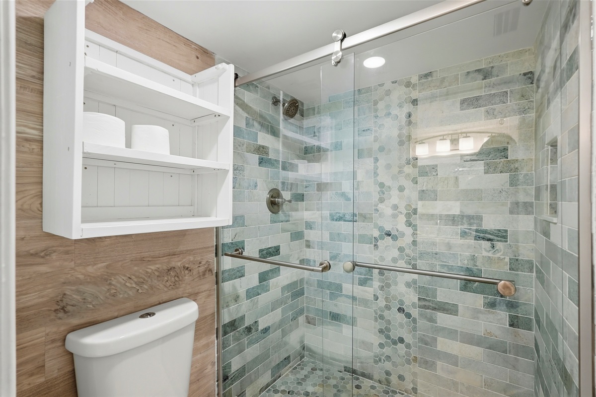 The common bathroom offers a clean, functional layout with a walk-in shower, toilet, and vanity. It also includes plenty of closet and storage space, providing added convenience for guests during their stay.