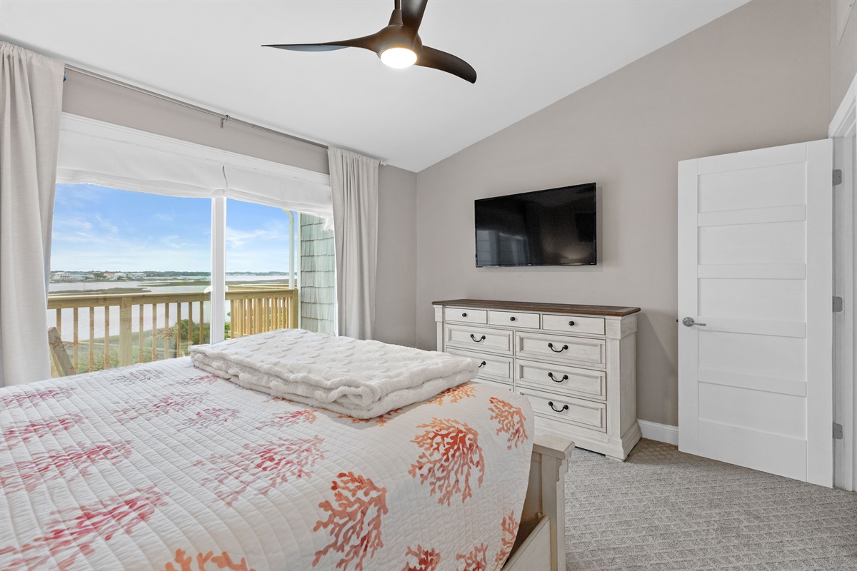 Master bedroom with Smart TV, dresser, and balcony access