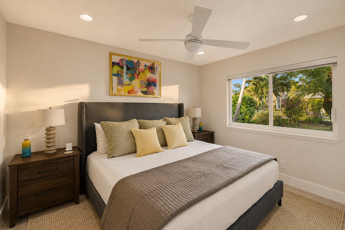 Rest in a bright king bedroom with soft bedding, tropical window views, a ceiling fan, and a calm place to recharge.