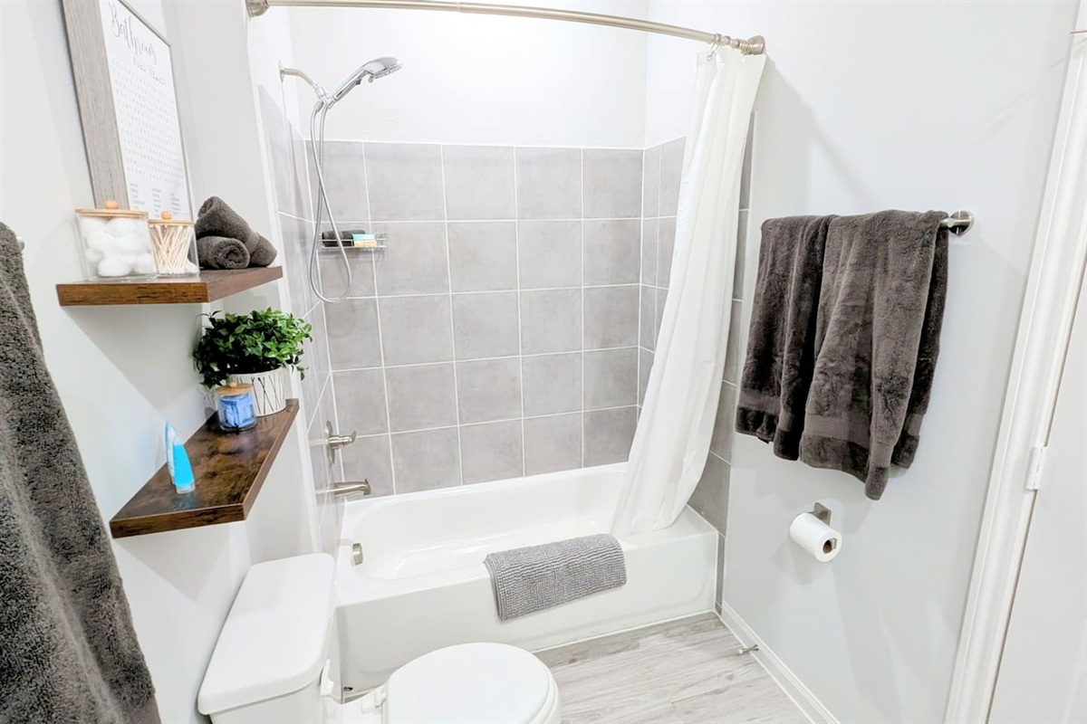 En suite bathroom located off the primary bedroom is fully stocked with fluffy towels, basic toiletries, and all the comforts of home. 