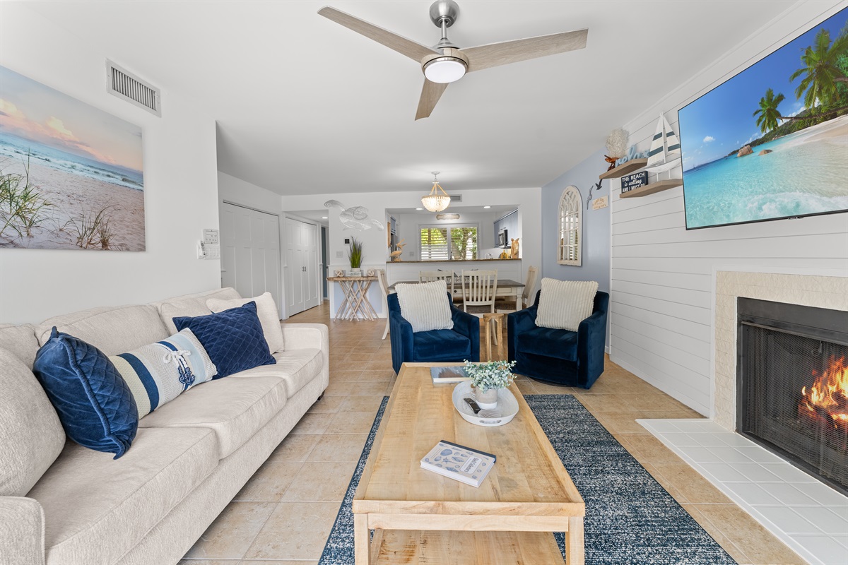 Spacious open Living room with fireplace, large TV and deck access.