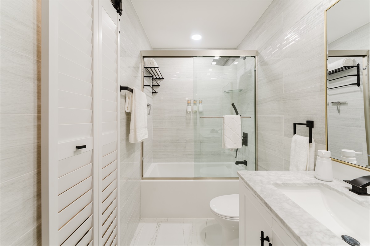 Spa-style **2nd bedroom ensuite bathroom** featuring a sleek glass-enclosed shower with rainfall head, marble vanity, and hotel-quality towels—clean, modern, and effortlessly relaxing.