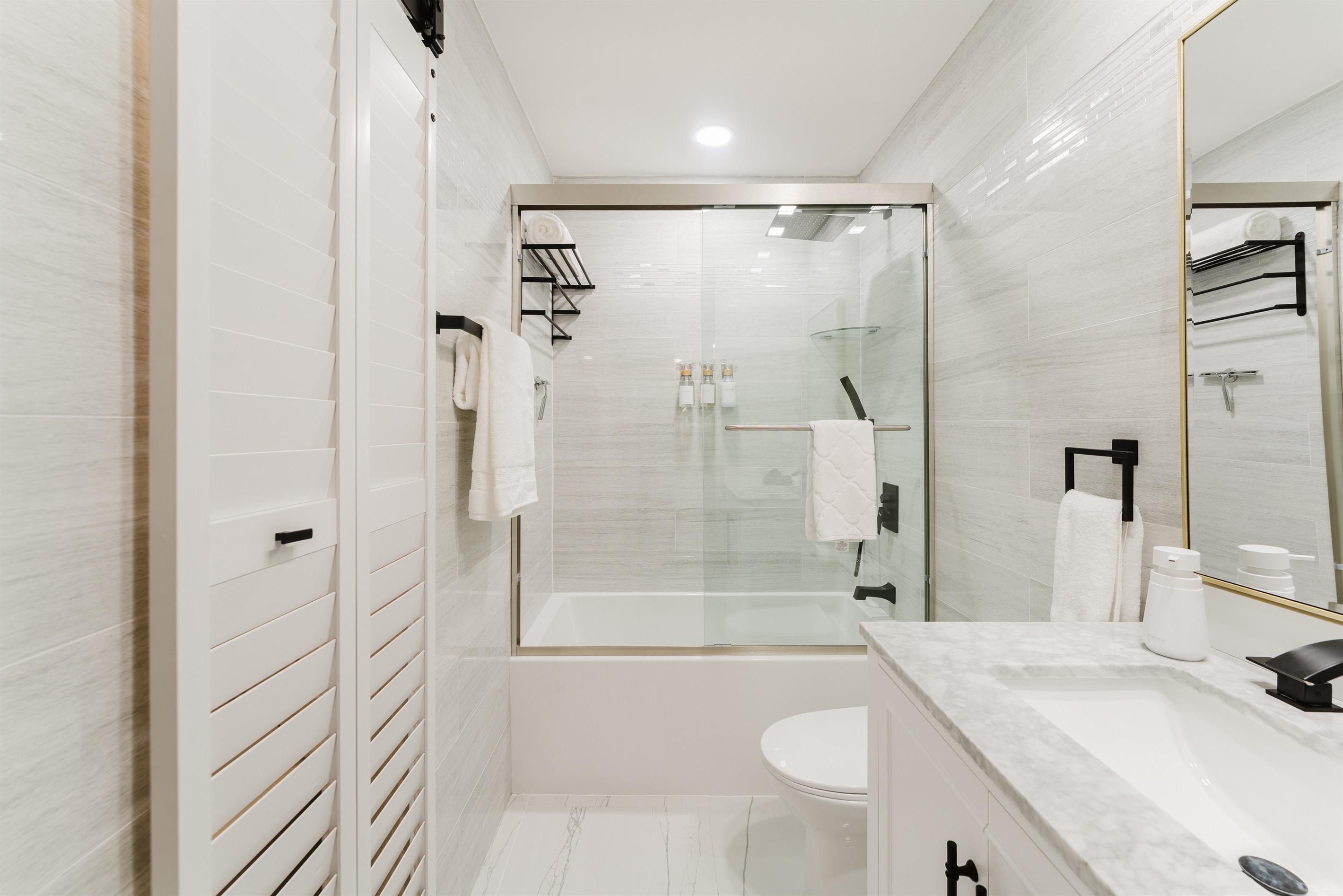 Spa-style **2nd bedroom ensuite bathroom** featuring a sleek glass-enclosed shower with rainfall head, marble vanity, and hotel-quality towels—clean, modern, and effortlessly relaxing.