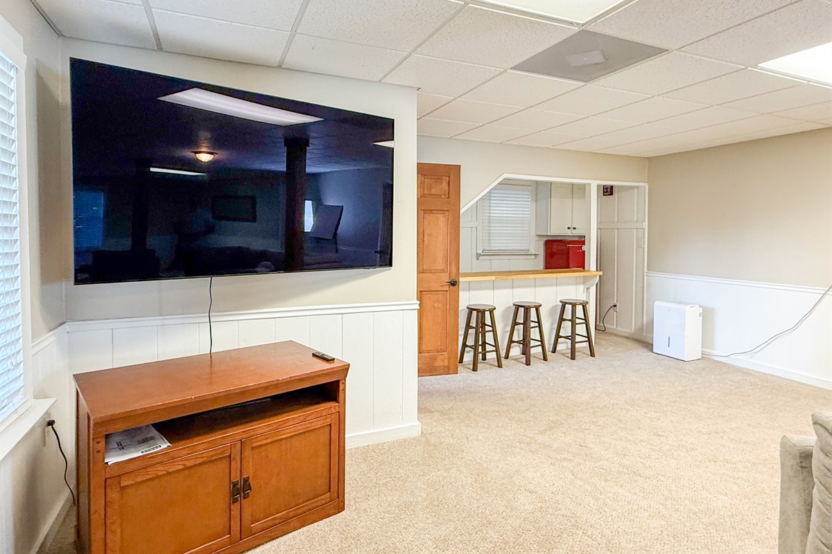 The basement kitchenette features a countertop with bar seating and a fridge for added convenience.