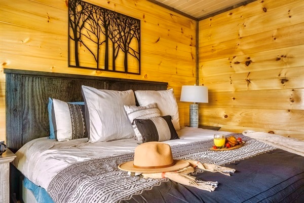 Stylish and modern bedroom decor featuring rustic wood accents, layered cozy pillows, and elegant wall art—designed for comfort and charm after your Smoky Mountain adventures.
