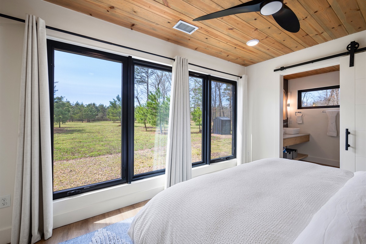 Wide windows fill this bedroom with natural light, giving it a bright, open feel while still maintaining a cozy atmosphere.
