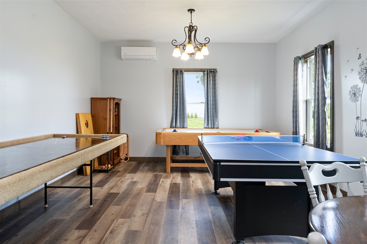 Entertainment-ready game room featuring a combination ping pong/pool table, shuffleboard, and air hockey with several board games and Cornhole for outside..... endless fun!