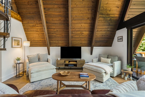 This cozy living space outfitted with a leather sofa and super comfortable chairs with ottomans for a perfect reading nook and relaxing area. This space is also great for movie nights with a smart TV you can use to connect to your own streaming apps.