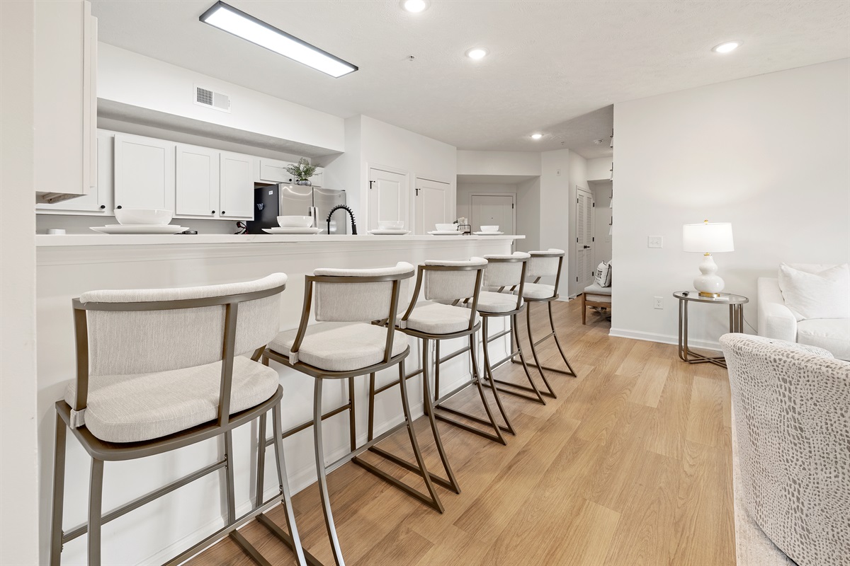 Cook, dine, and unwind together—open living with a stocked kitchen and five bar stools.