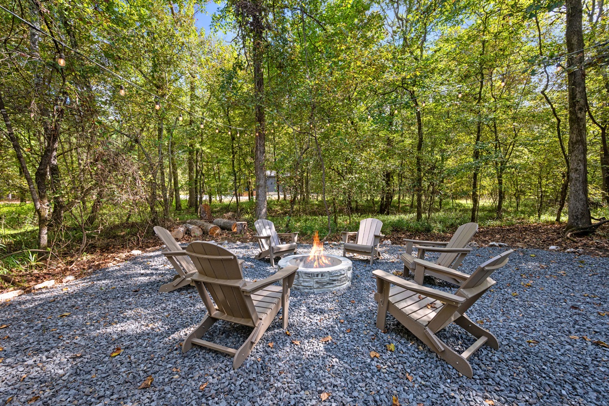 Firepit area with Adirondack chairs under the trees.