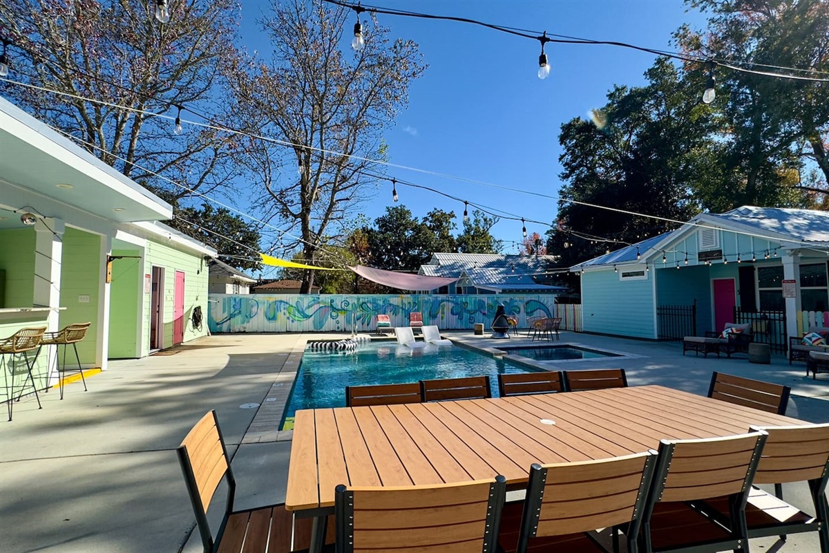 POV from the communal table overlooking the pool, colorful cottages, and relaxed outdoor gathering space.