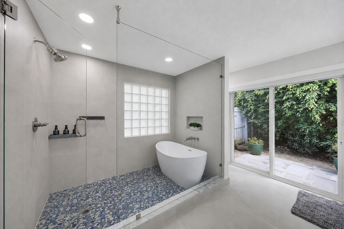 Unwind in a spa-style bathroom with a soaking tub, glass shower, blue mosaic floor, and private garden-facing doors.