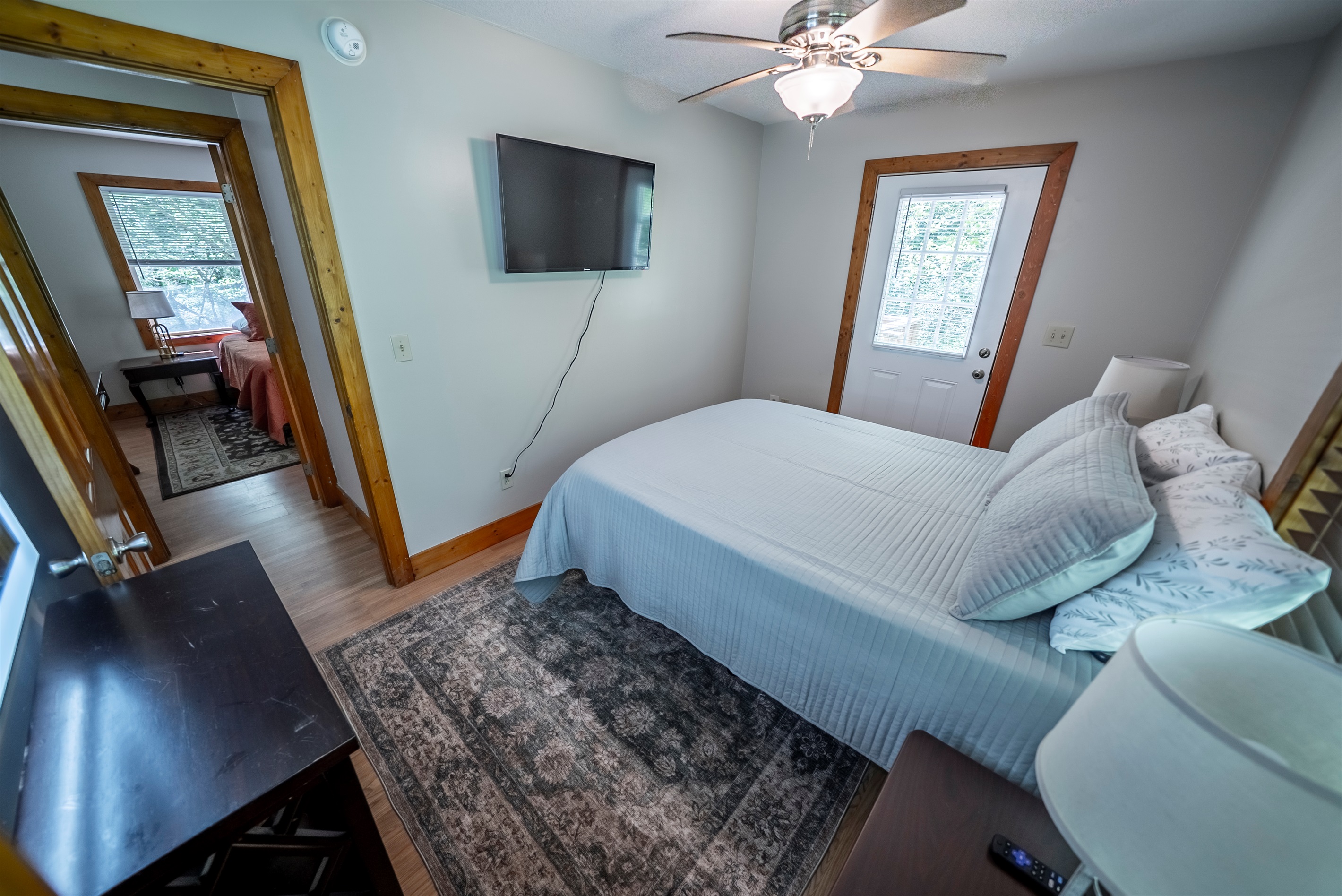 Relax in the queen guest room featuring a Smart TV, ceiling fan, and a private exterior door leading right out to the deck.