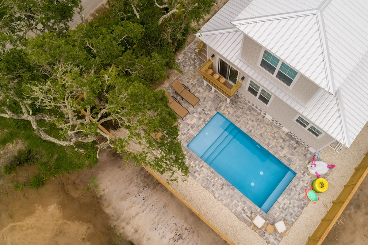 From above you can see how the whole back of the property is given over to the pool - pavers, loungers, and a fence around all of it. The rear steps come down from the living room, so the water is never far.