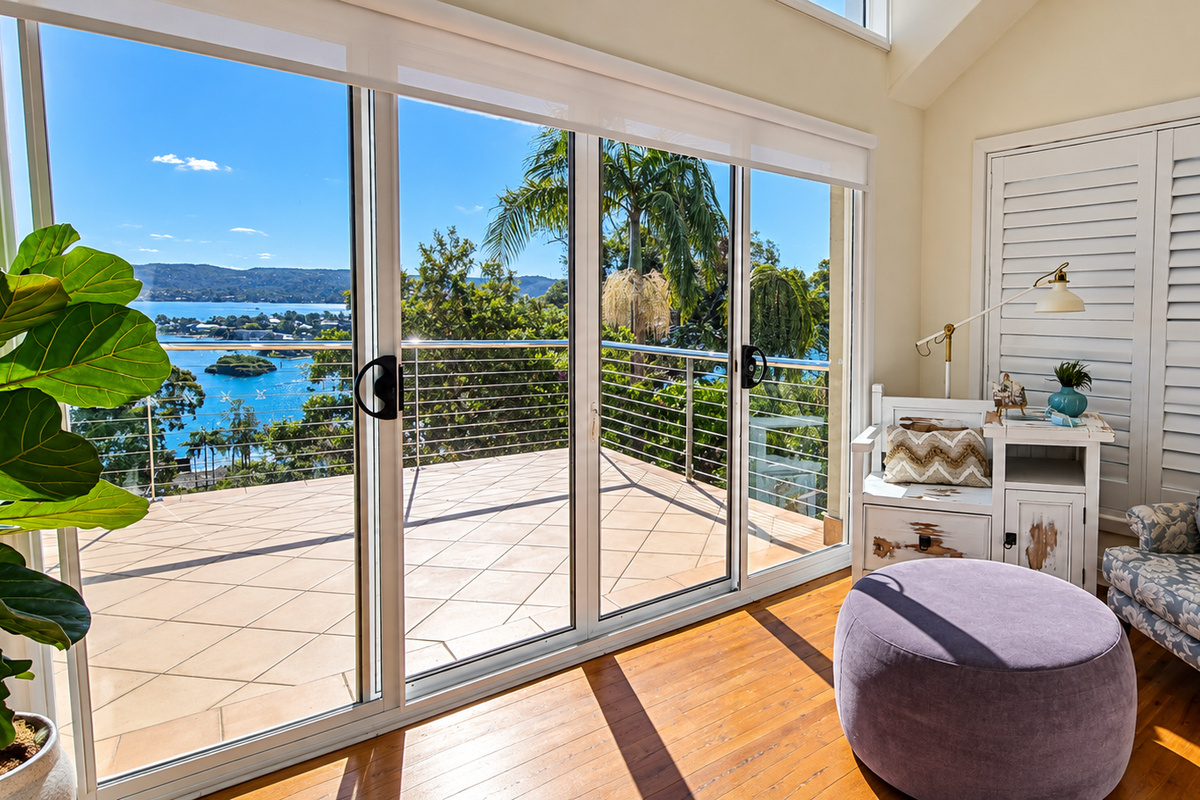 A peaceful reading nook opening onto a sun-drenched balcony with beautiful water and mountain views.