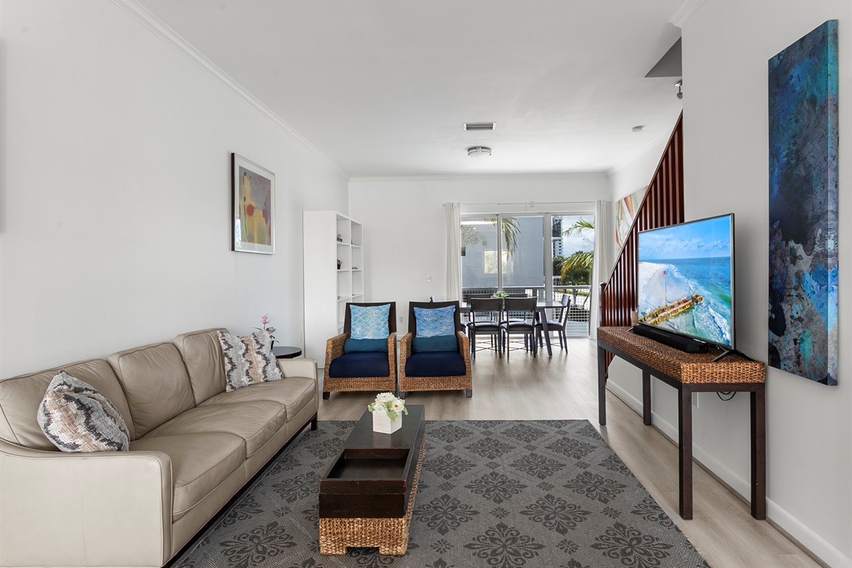 Living room with leather sofa, accent chairs, and a 50-inch flat screen TV.