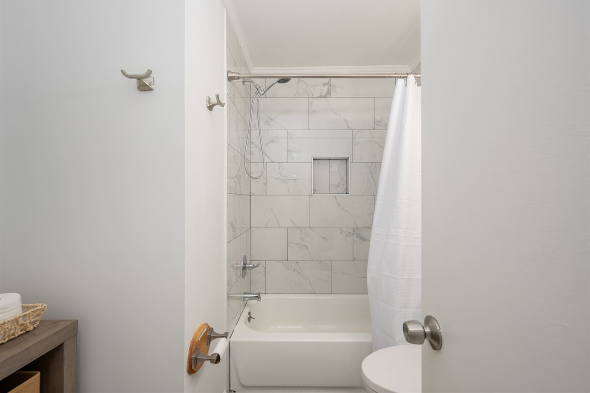 Bathroom with new tile shower, vanity, fixtures, and additional storage space.