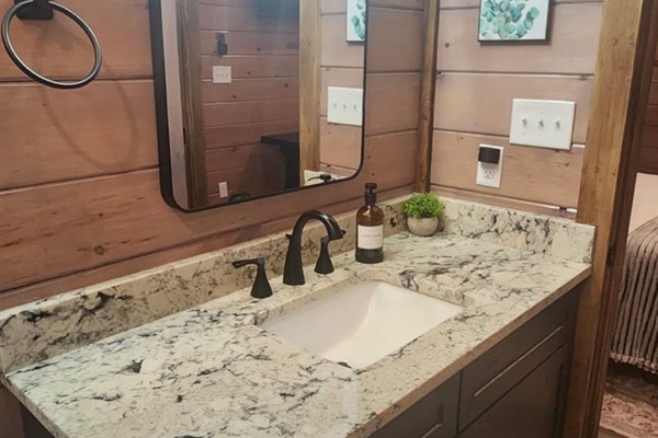 Single vanity bathroom with granite countertop and modern black fixtures.
