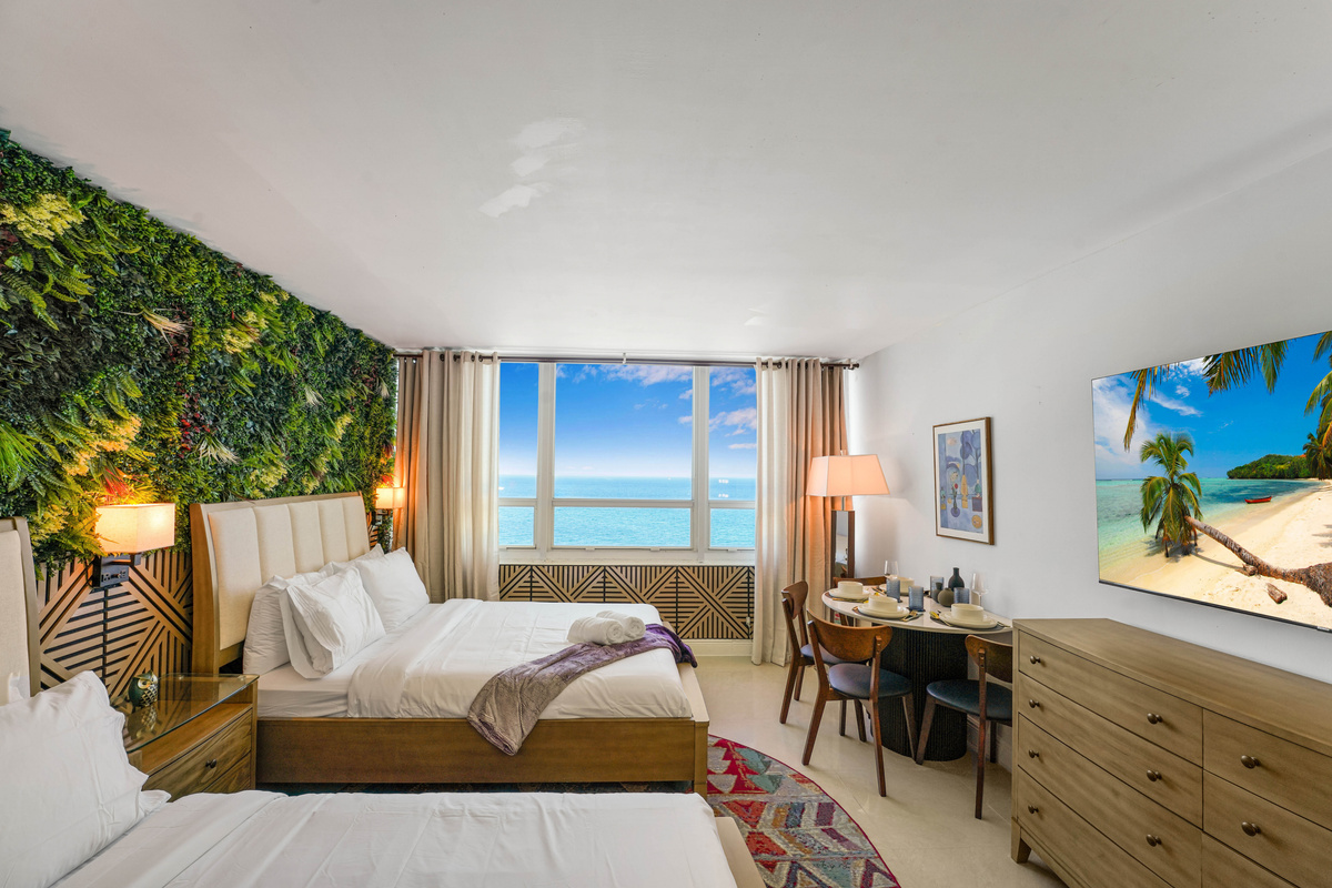 The studio's sleeping area, with two queen beds, a lush greenery feature wall and a wide window looking straight out over the Atlantic.