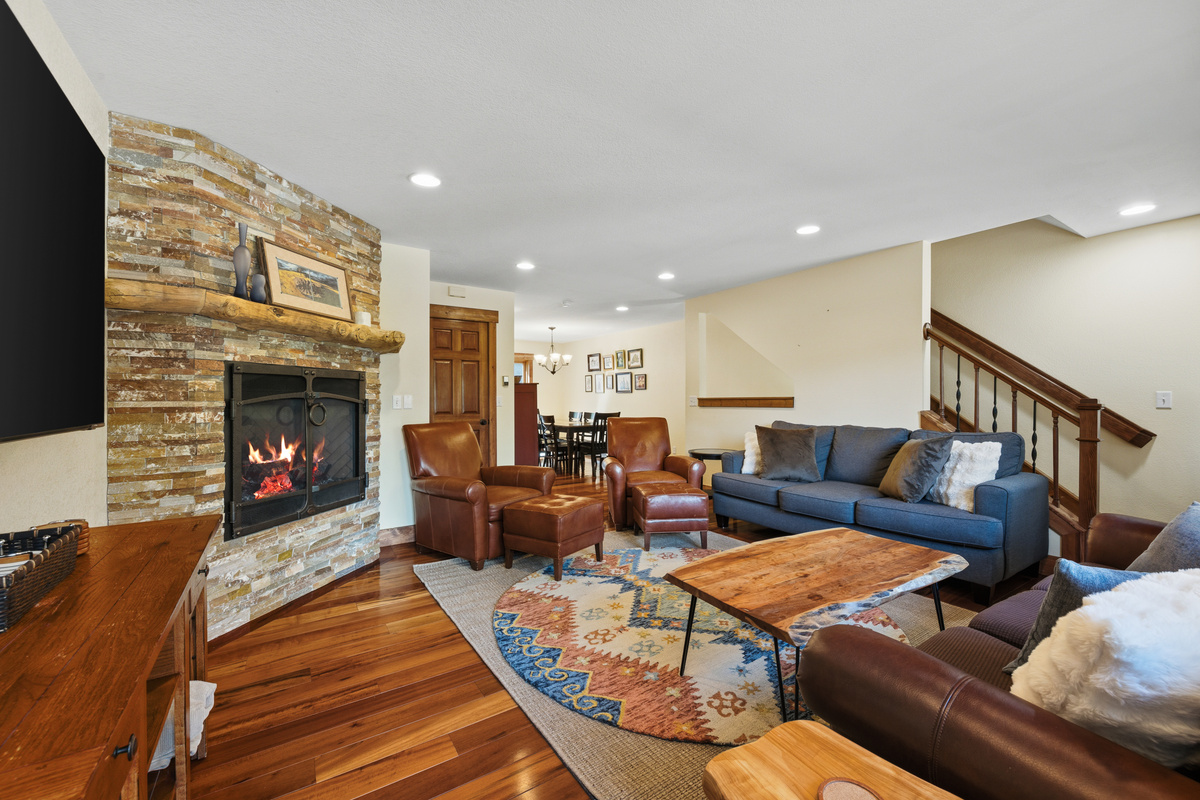 Spacious living room with warm gas fireplace and dining/kitchen seen in background