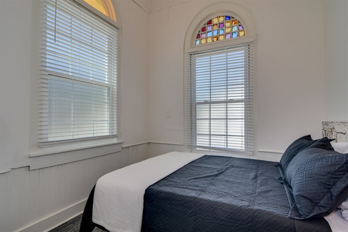 Guest suite with cozy queen bed and tall window.
