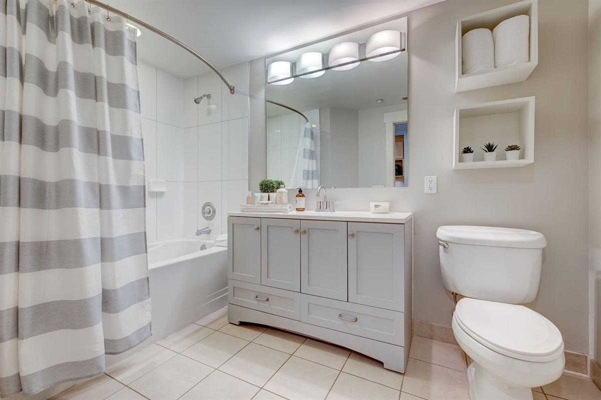 Full bathroom has a tiled shower/tub combo with bowing shower curtain rod to allow for even more space in the shower.