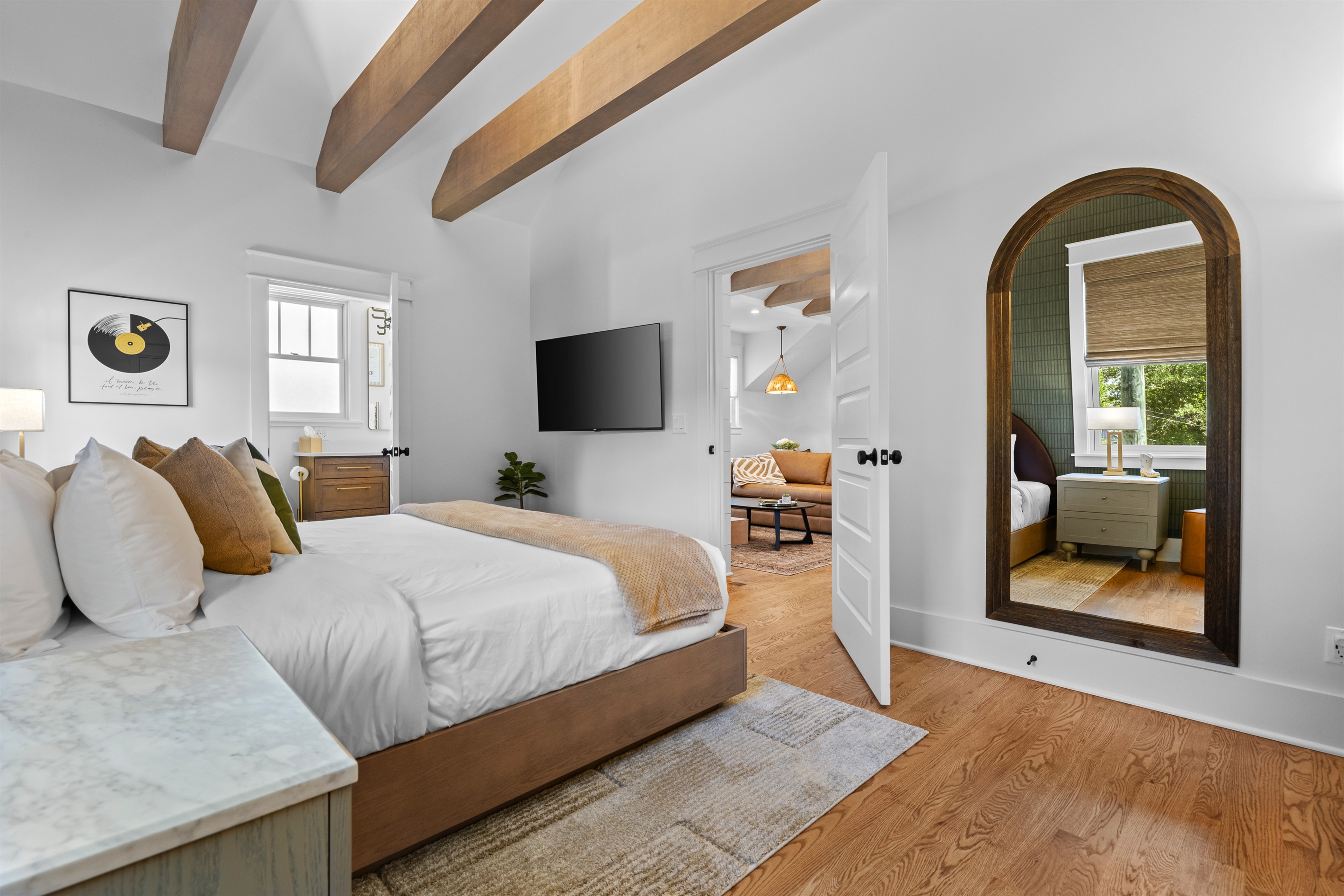 Spacious bedroom with Smart TV and full-length mirror.