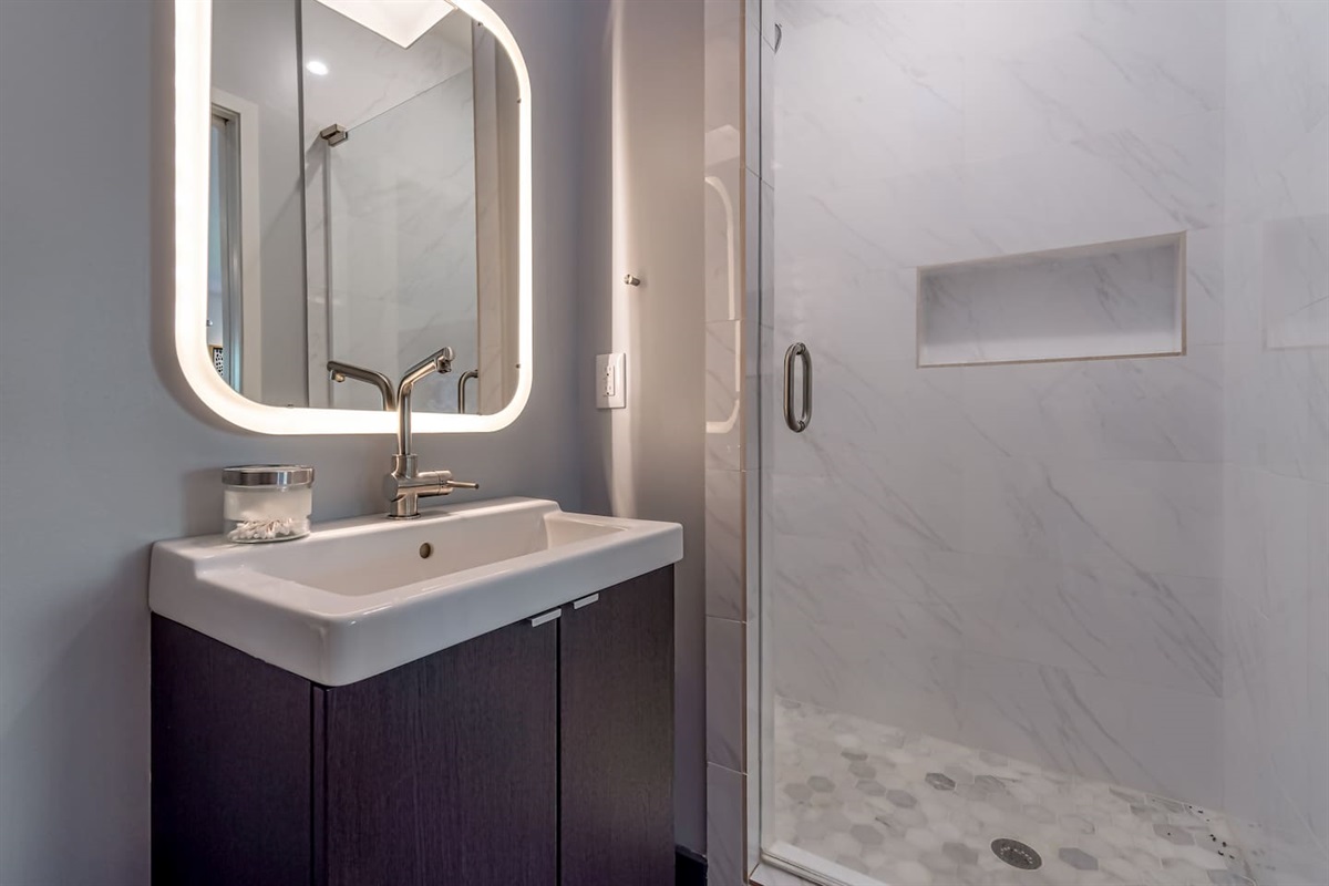 Full bath with walk in shower located in bunk room/game room and just outside bedroom with convertible chairs