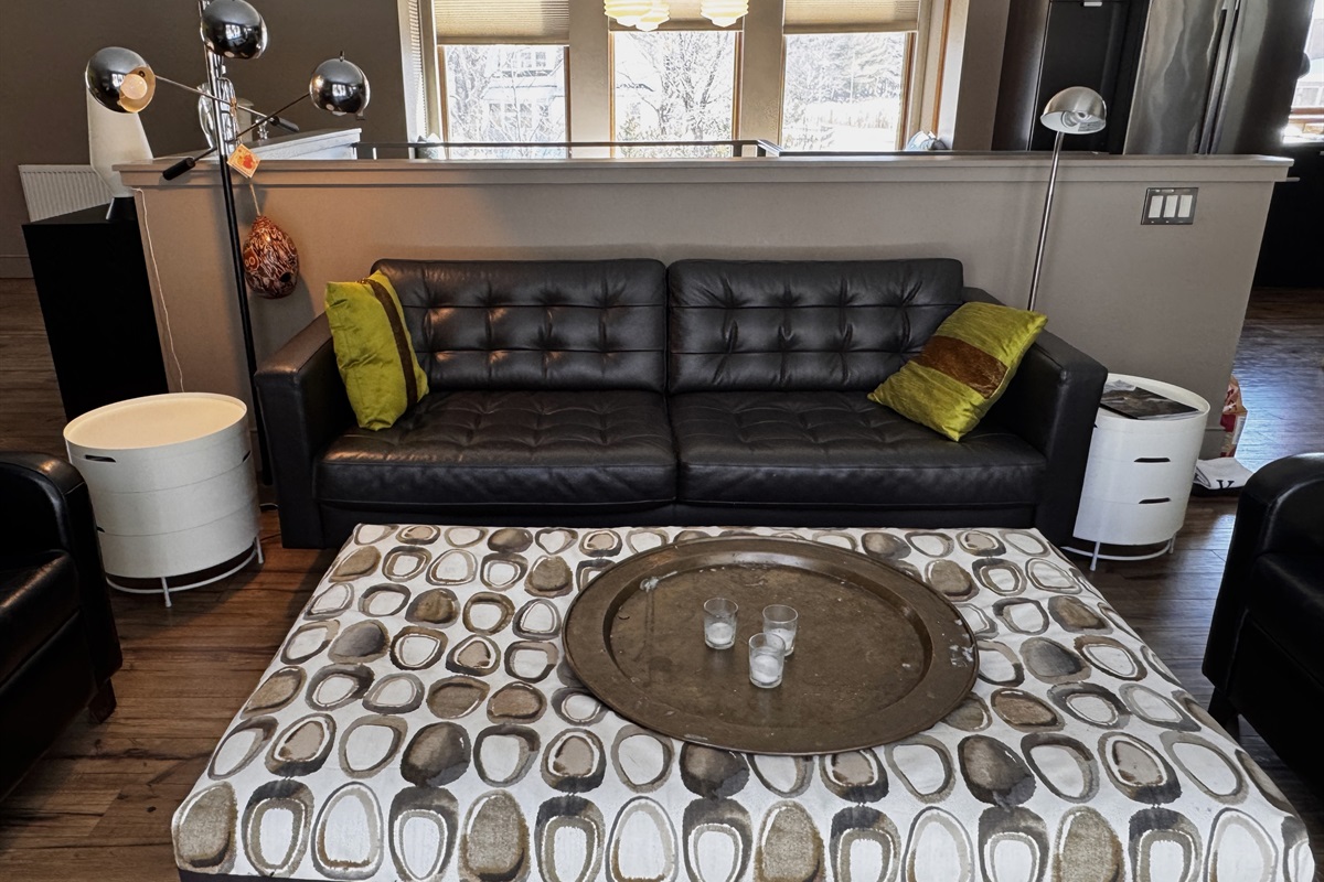 The main level sitting area features modern leather seating and intentional designer touches. Positioned directly across from a wall of windows, this space offers uninterrupted views of the 33ft deck and the quiet Acadia National Park border.