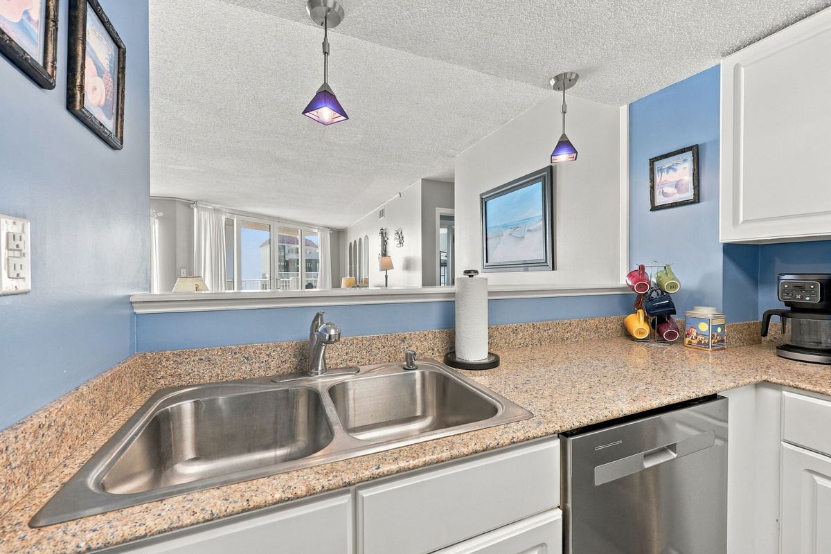Kitchen area view featuring light blue accent walls, granite countertops, and a double-basin sink.