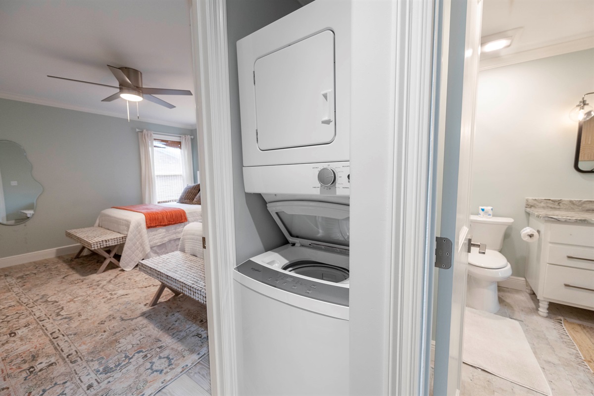 Cozy bedroom with a ceiling fan, en-suite bathroom, and laundry unit for modern convenience and comfort.
