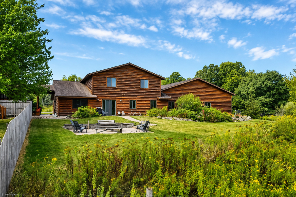 Wide exterior view of the lodge, patio, fire pit, and surrounding grounds, showcasing the outdoor gathering space and peaceful Northwoods setting your group can enjoy throughout the stay.