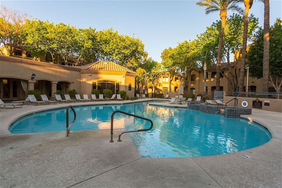Community pool area with lounge chairs, shaded seating, and a resort-style outdoor setting.