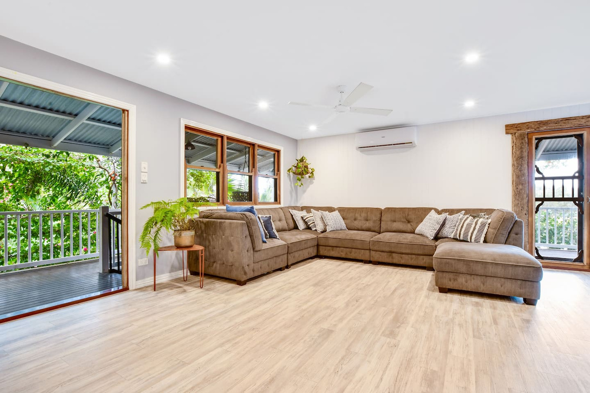 Large openings bring garden greenery into view from the living room at Aaron's Beachside Boat House, creating a bright, relaxed indoor setting.