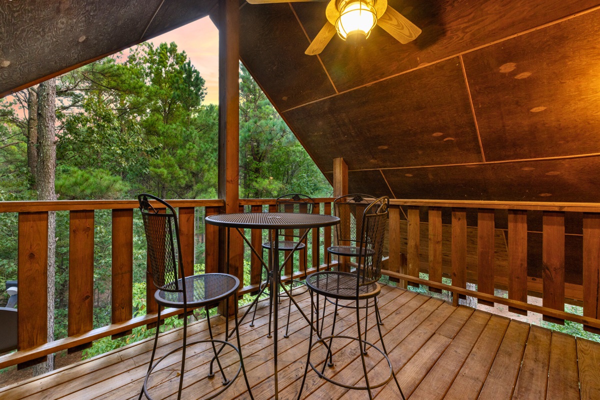 Upper balcony with seating and forest views at sunset.
