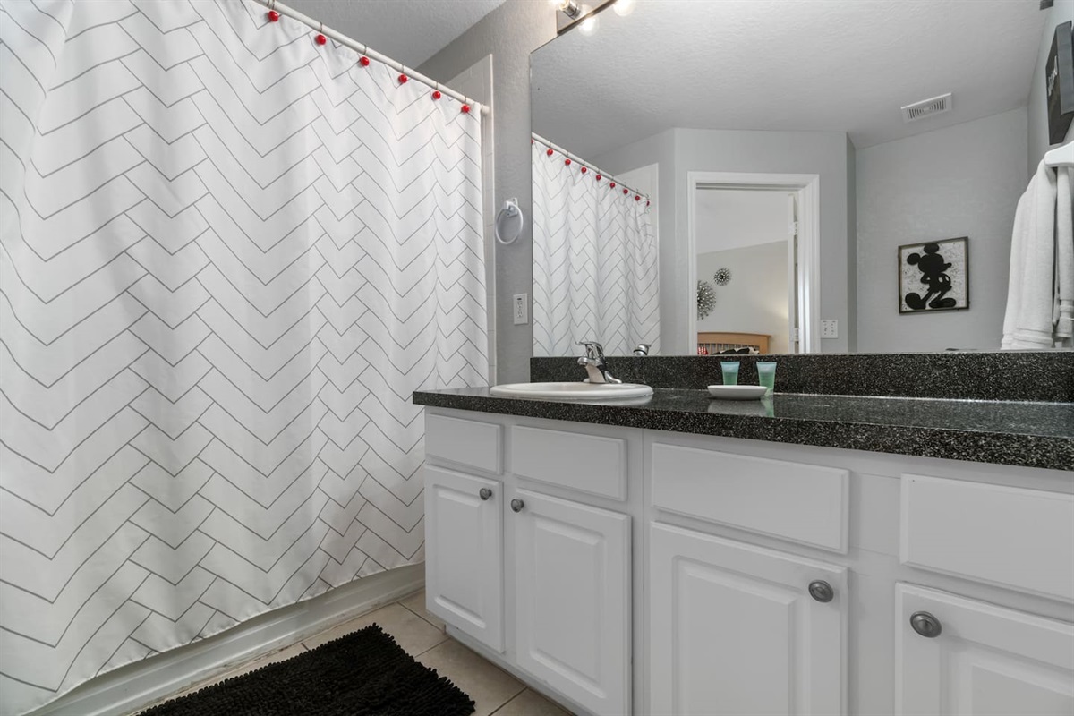 - Sleek bathroom with white cabinetry, granite countertop, and large mirror  
- Chevron pattern shower curtain adds a modern touch to the clean design  
- Functional layout ideal for refreshing after a day of adventures  